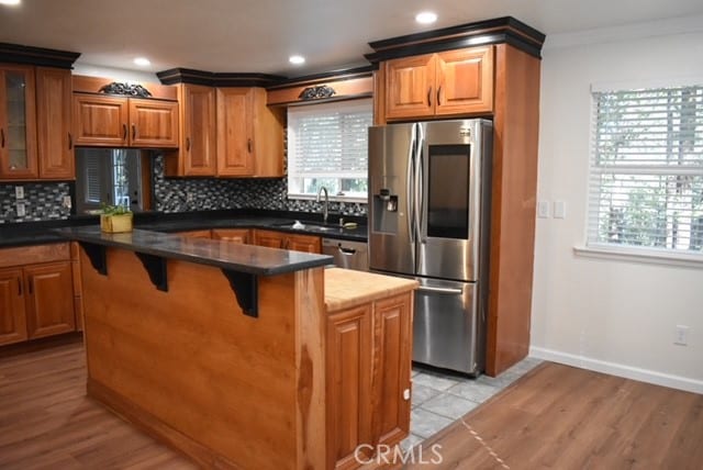 kitchen with light hardwood / wood-style floors, tasteful backsplash, stainless steel appliances, and a kitchen island