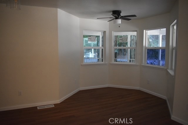 unfurnished room featuring dark wood-type flooring and ceiling fan