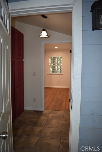 corridor with lofted ceiling and dark tile patterned flooring