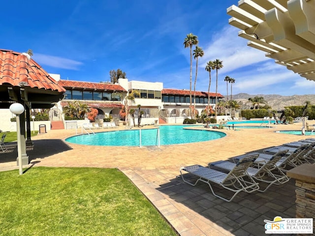 view of swimming pool with a yard, a mountain view, and a patio area