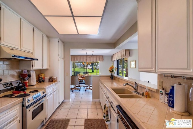 kitchen with sink, electric stove, tile countertops, white cabinetry, and decorative backsplash