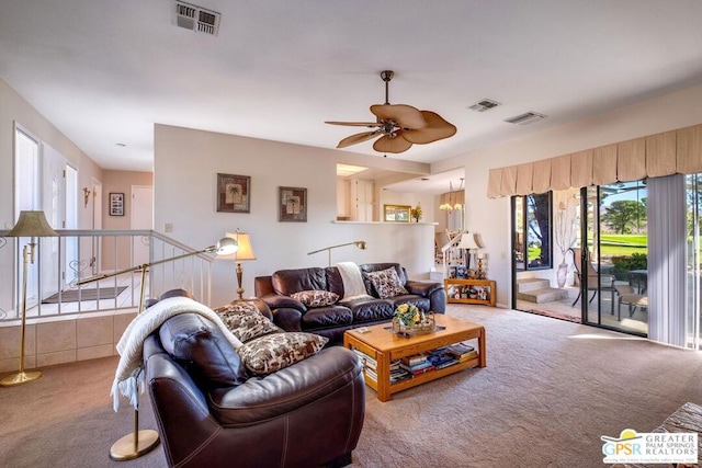 carpeted living room featuring ceiling fan with notable chandelier