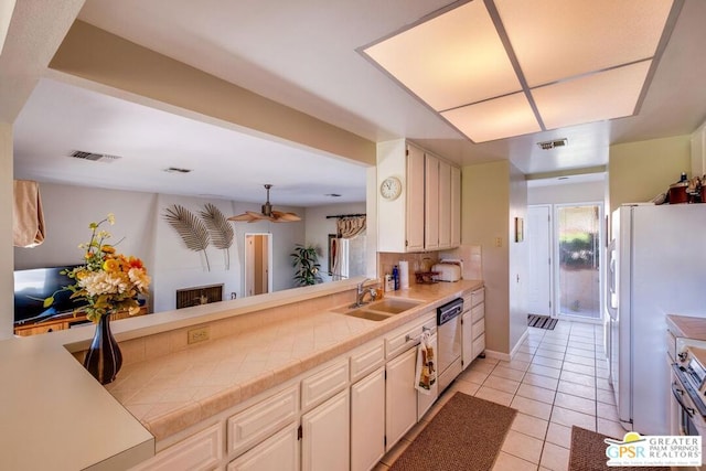 kitchen with tile countertops, dishwasher, light tile patterned flooring, white fridge, and sink