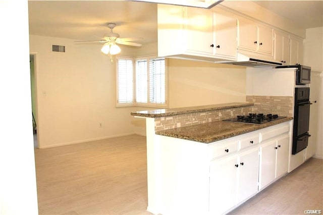 kitchen featuring tasteful backsplash, white cabinets, black appliances, and light hardwood / wood-style floors