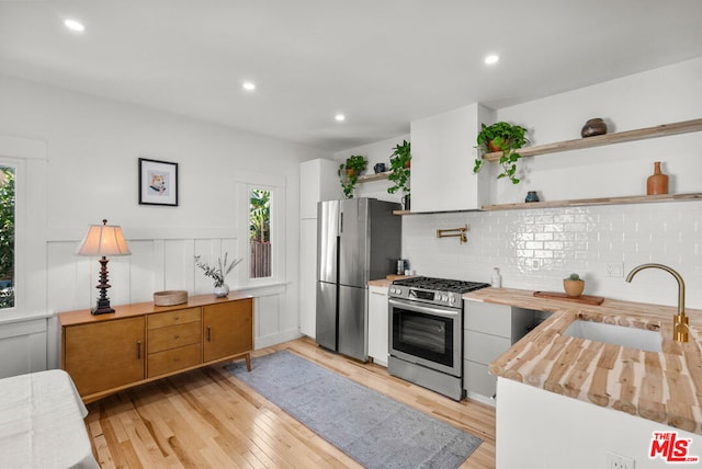 kitchen featuring stainless steel appliances, light hardwood / wood-style floors, a healthy amount of sunlight, and sink