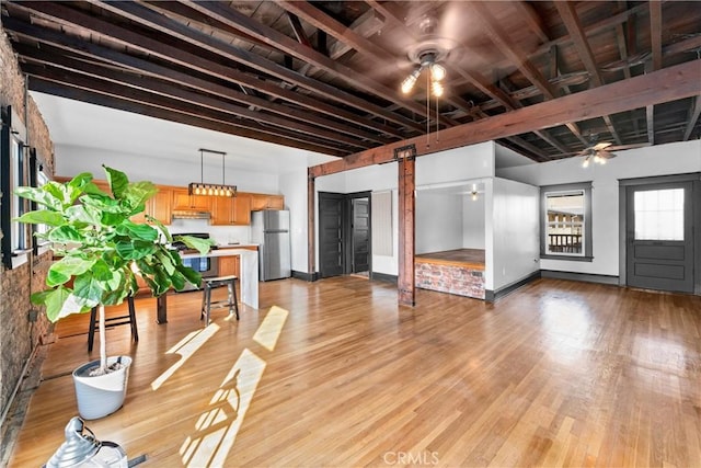 interior space featuring beam ceiling, a barn door, ceiling fan, and light wood-type flooring