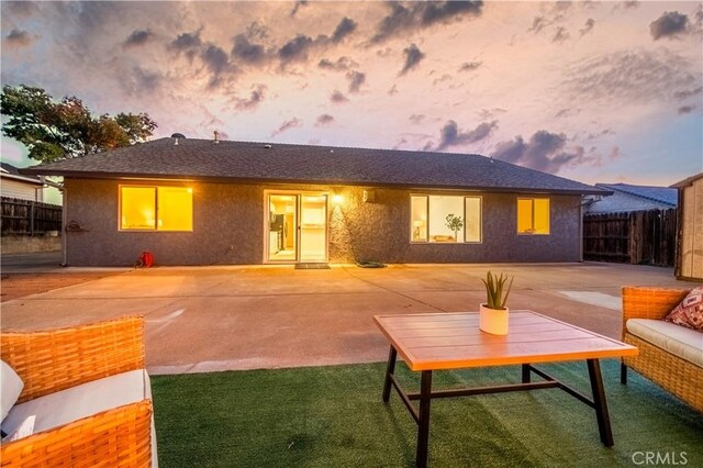 back house at dusk with a patio area