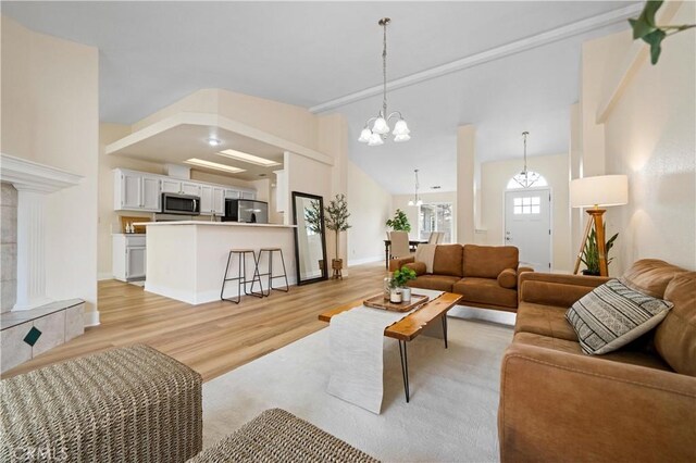 living room featuring high vaulted ceiling, light wood-type flooring, and an inviting chandelier