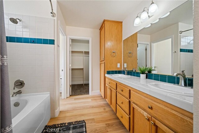 bathroom featuring hardwood / wood-style flooring, tiled shower / bath combo, and vanity