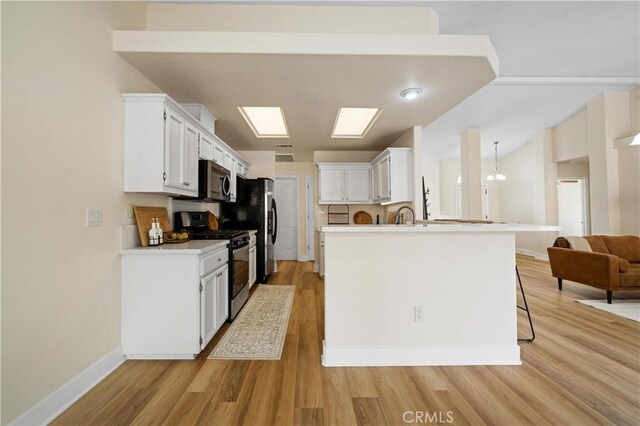 kitchen with kitchen peninsula, stainless steel appliances, white cabinetry, and light hardwood / wood-style floors