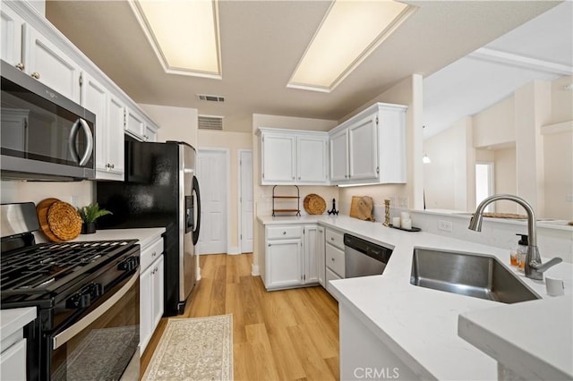 kitchen featuring sink, white cabinets, stainless steel appliances, and light wood-type flooring