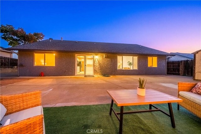 back house at dusk featuring a patio area