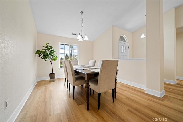 dining area featuring light hardwood / wood-style flooring, a chandelier, and vaulted ceiling