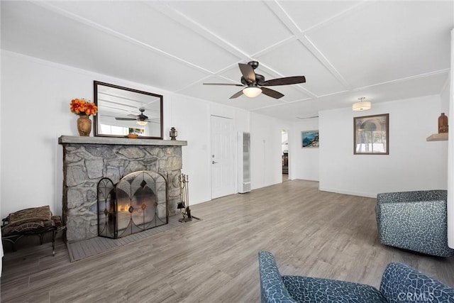 living room with hardwood / wood-style flooring, a stone fireplace, ceiling fan, and coffered ceiling