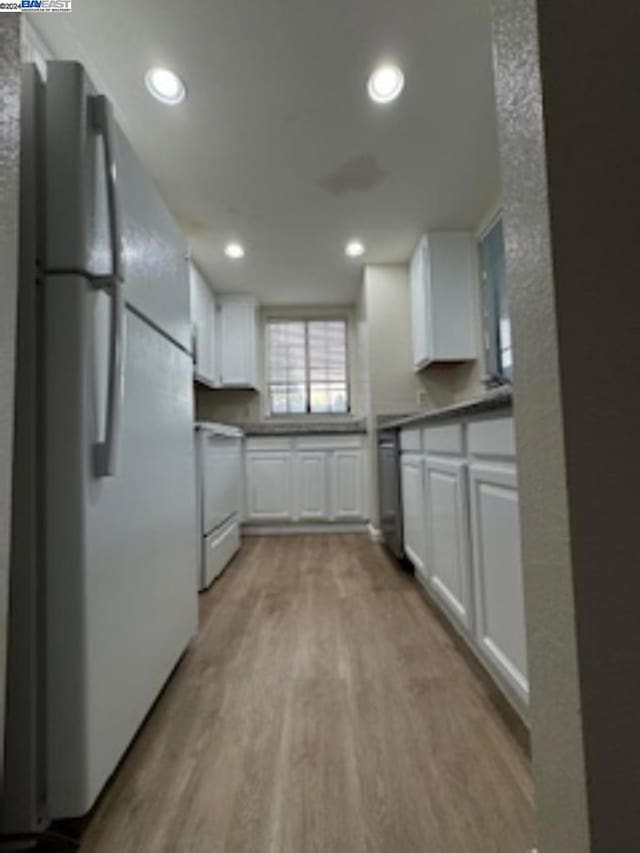 kitchen with white appliances, light hardwood / wood-style floors, and white cabinetry