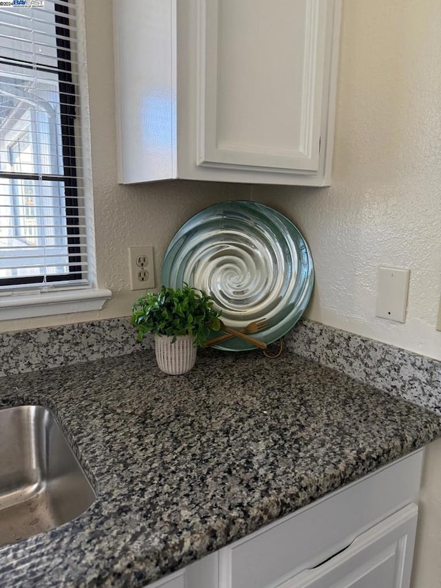 interior details with white cabinets and dark stone countertops