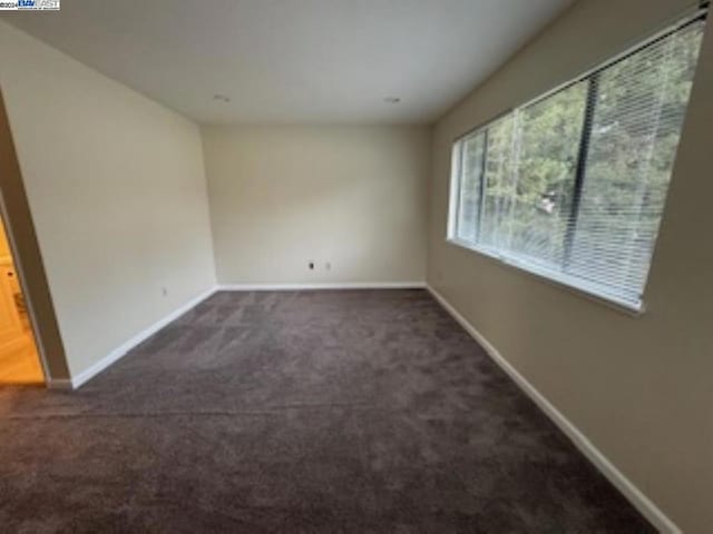 unfurnished room with dark colored carpet