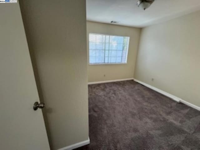 spare room featuring dark colored carpet