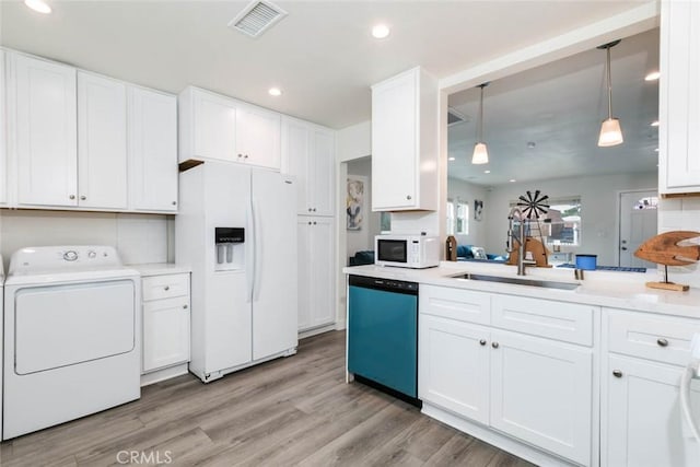 kitchen featuring white appliances, decorative light fixtures, washer / dryer, light hardwood / wood-style floors, and white cabinetry