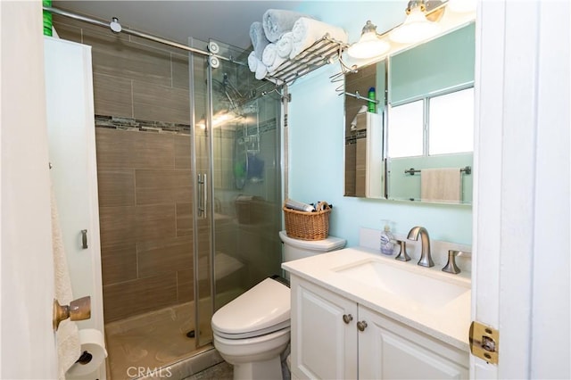 bathroom with a stall shower, vanity, and toilet