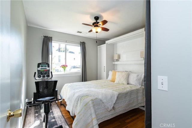 bedroom featuring a ceiling fan, visible vents, and wood finished floors