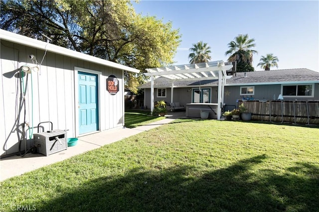 back of house featuring a pergola, a yard, and a hot tub