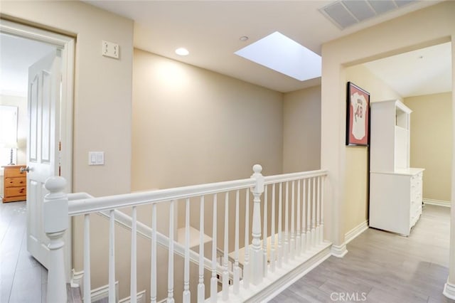 hall with light wood-type flooring and a skylight