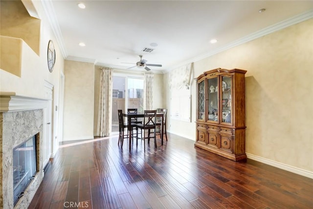 dining area with ceiling fan, dark hardwood / wood-style flooring, ornamental molding, and a fireplace