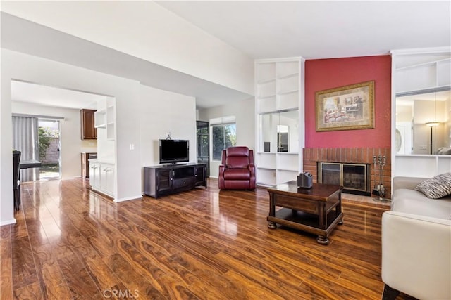 living room with vaulted ceiling, dark hardwood / wood-style floors, and a fireplace