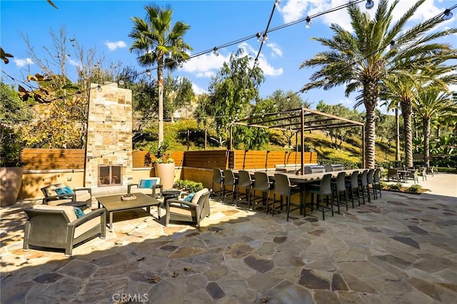 view of patio featuring an outdoor living space with a fireplace and an outdoor bar