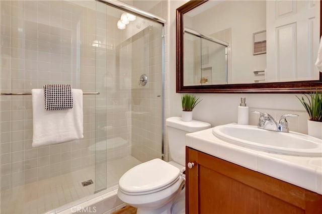 bathroom featuring vanity, an enclosed shower, and toilet