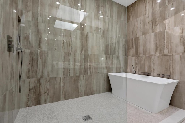 bathroom featuring shower with separate bathtub and tile walls