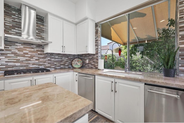 kitchen with white cabinets, sink, wall chimney range hood, and stainless steel appliances