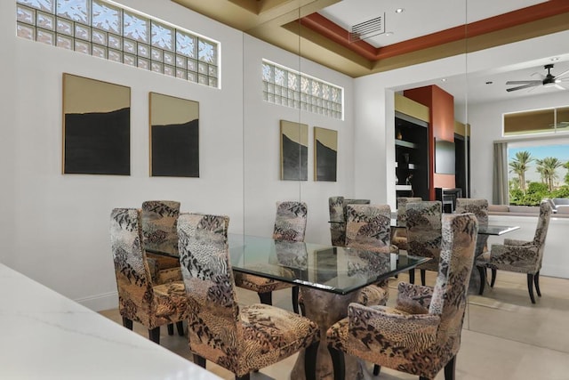 dining space featuring ceiling fan with notable chandelier, a towering ceiling, and a wealth of natural light