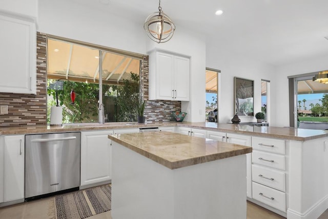 kitchen featuring white cabinetry, hanging light fixtures, tasteful backsplash, stainless steel dishwasher, and a kitchen island