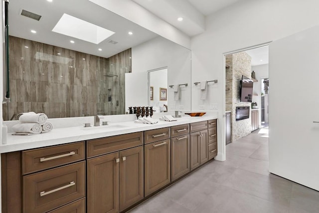 bathroom featuring vanity, tiled shower, and a skylight