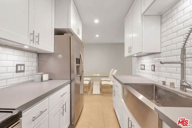 kitchen with white cabinets, decorative backsplash, light tile patterned floors, and sink