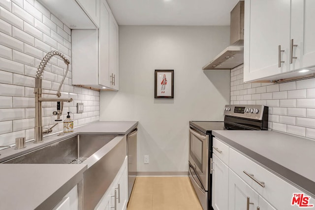 kitchen featuring white cabinetry, sink, stainless steel appliances, wall chimney range hood, and backsplash