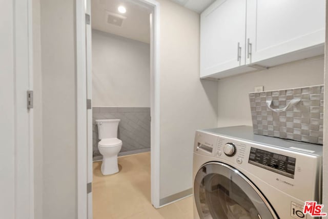 washroom featuring cabinets, light tile patterned floors, tile walls, and washer / clothes dryer