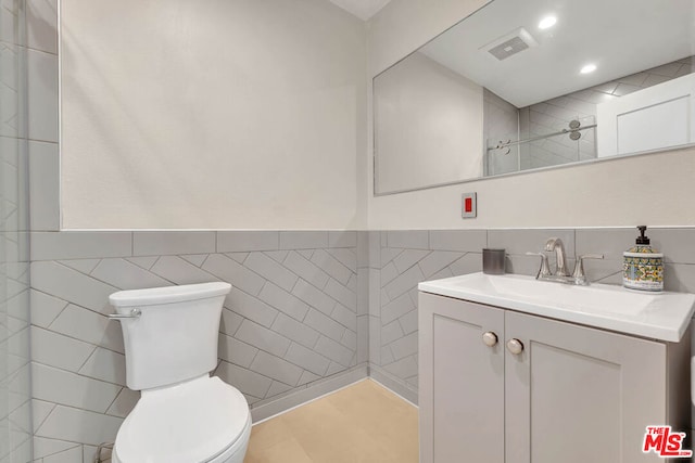 bathroom featuring vanity, toilet, and tile walls