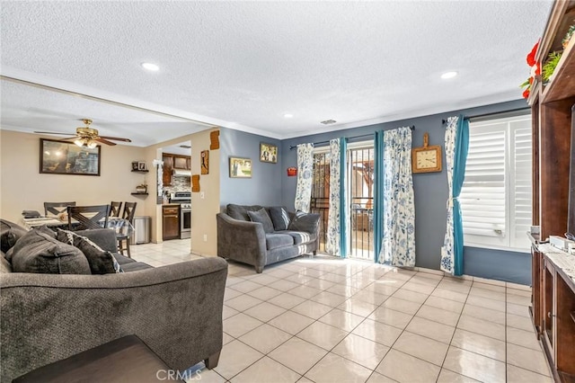 living room with crown molding, ceiling fan, light tile patterned flooring, and a textured ceiling