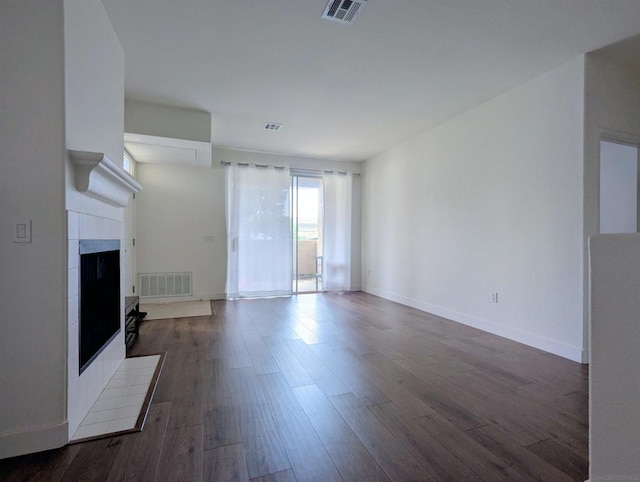 unfurnished living room featuring dark hardwood / wood-style flooring and a tile fireplace