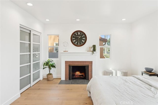 bedroom featuring a brick fireplace and light hardwood / wood-style flooring