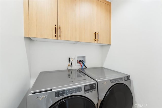 clothes washing area with washing machine and dryer and cabinets