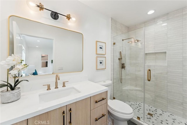 bathroom featuring vanity, toilet, and a shower with shower door