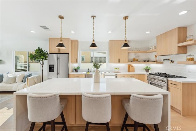 kitchen with light stone countertops, a center island, hanging light fixtures, backsplash, and appliances with stainless steel finishes