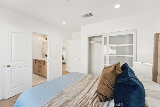 bedroom featuring light wood-type flooring, connected bathroom, and a closet