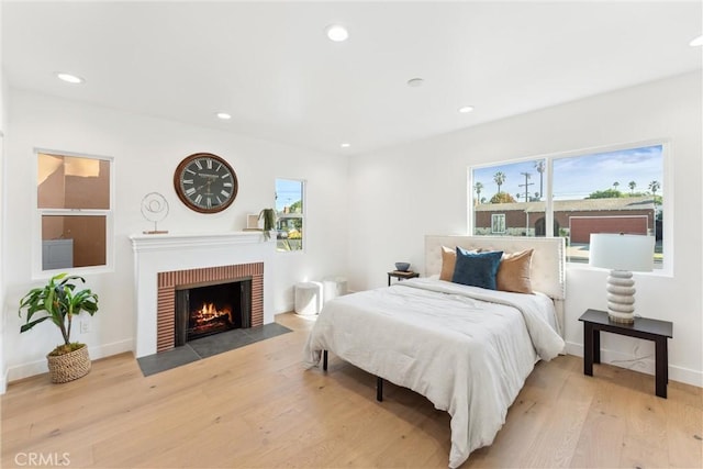 bedroom with light wood-type flooring and a brick fireplace