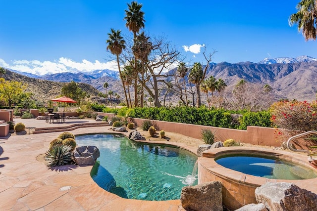 view of pool featuring a patio, a mountain view, pool water feature, and an in ground hot tub