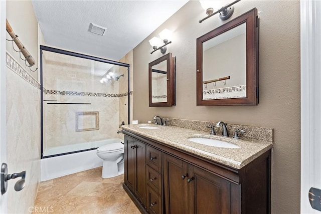 full bathroom featuring toilet, a textured ceiling, vanity, and shower / bath combination with glass door